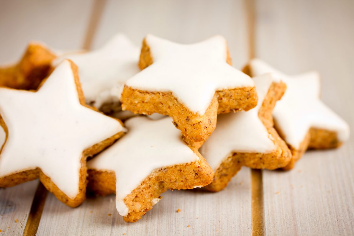Zimtsterne, star-shaped cinnamon cookies with white meringue icing, on a wooden table