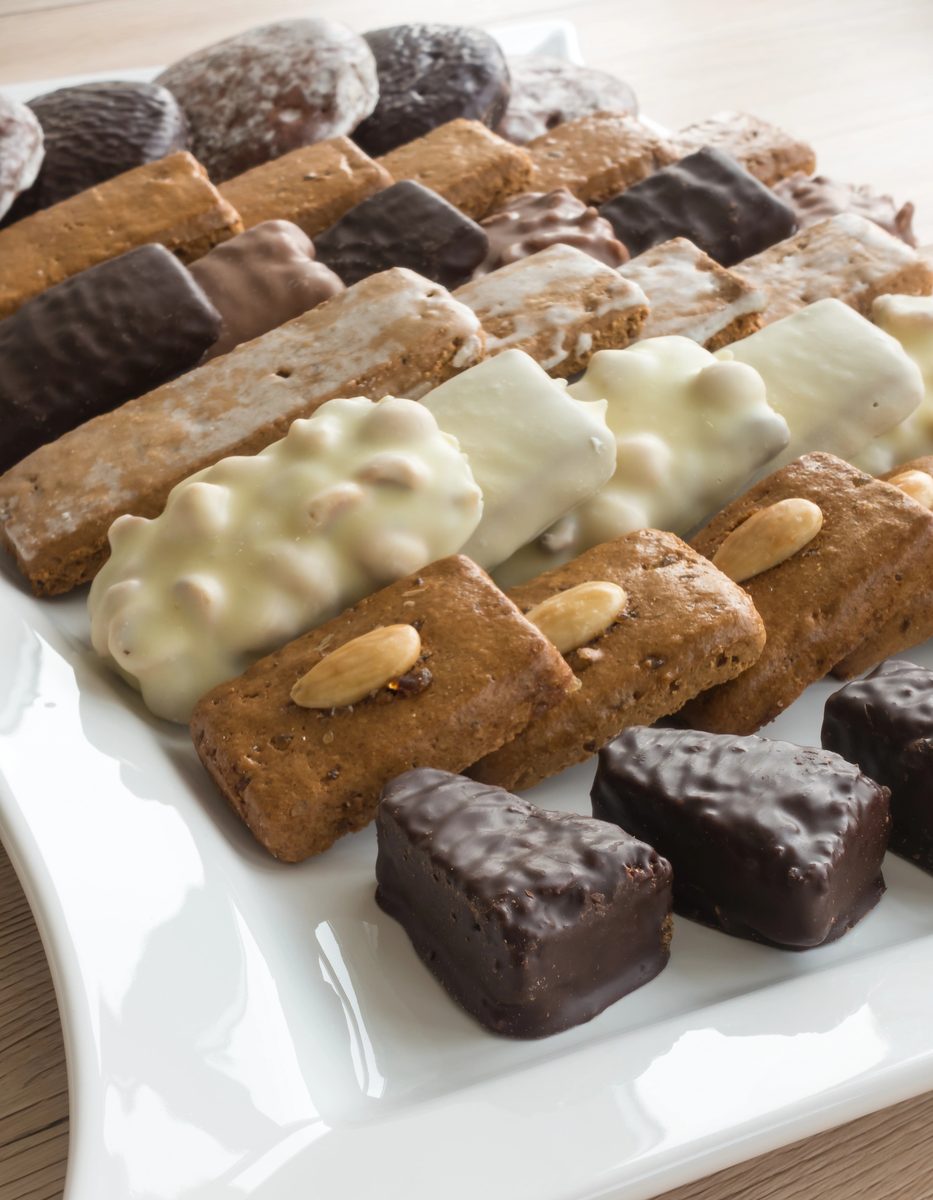 Assorted German gingerbread, including glazed and chocolate-coated Aachener Printen, on a white plate