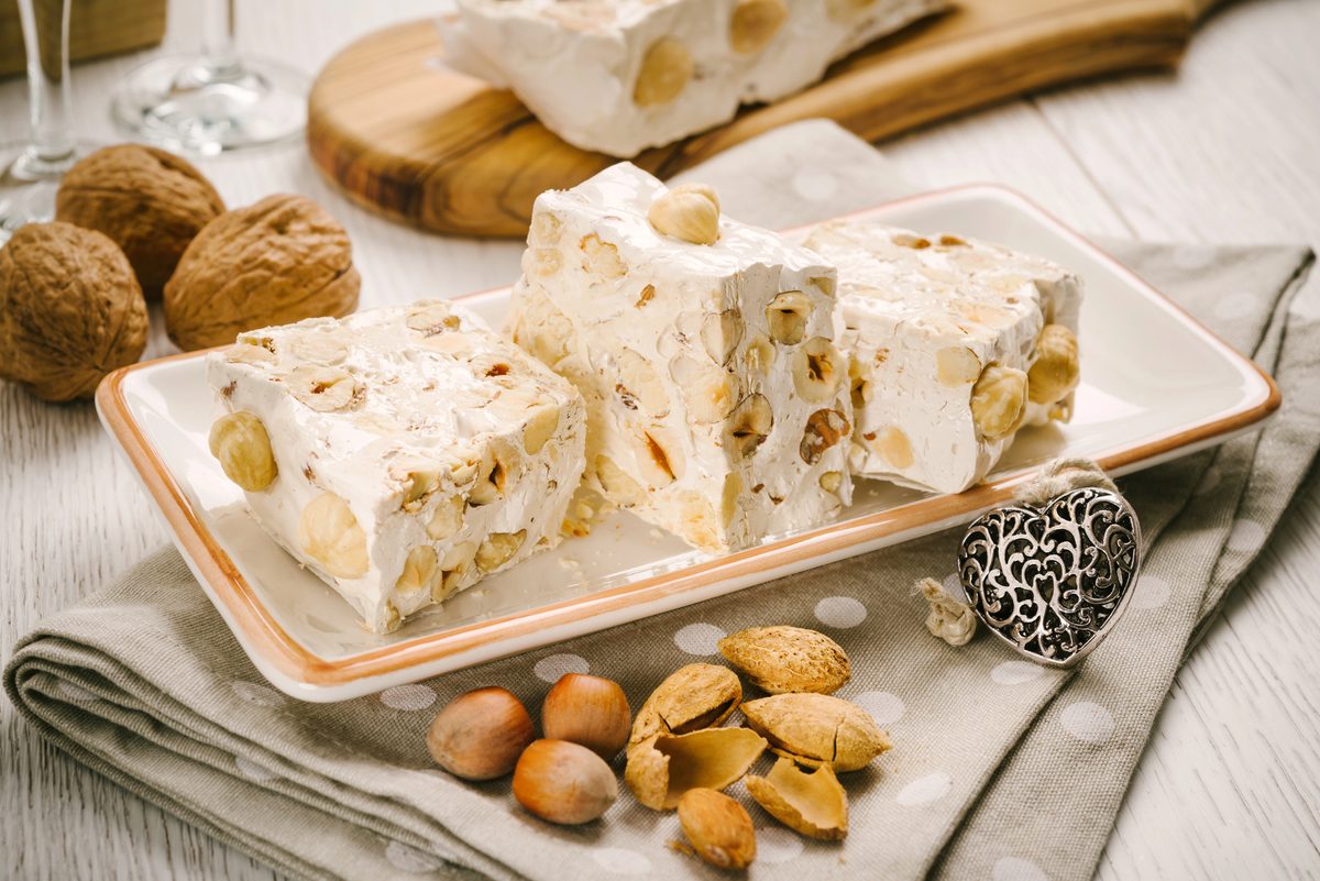 Pieces of almond turrón nougat on a plate with nuts