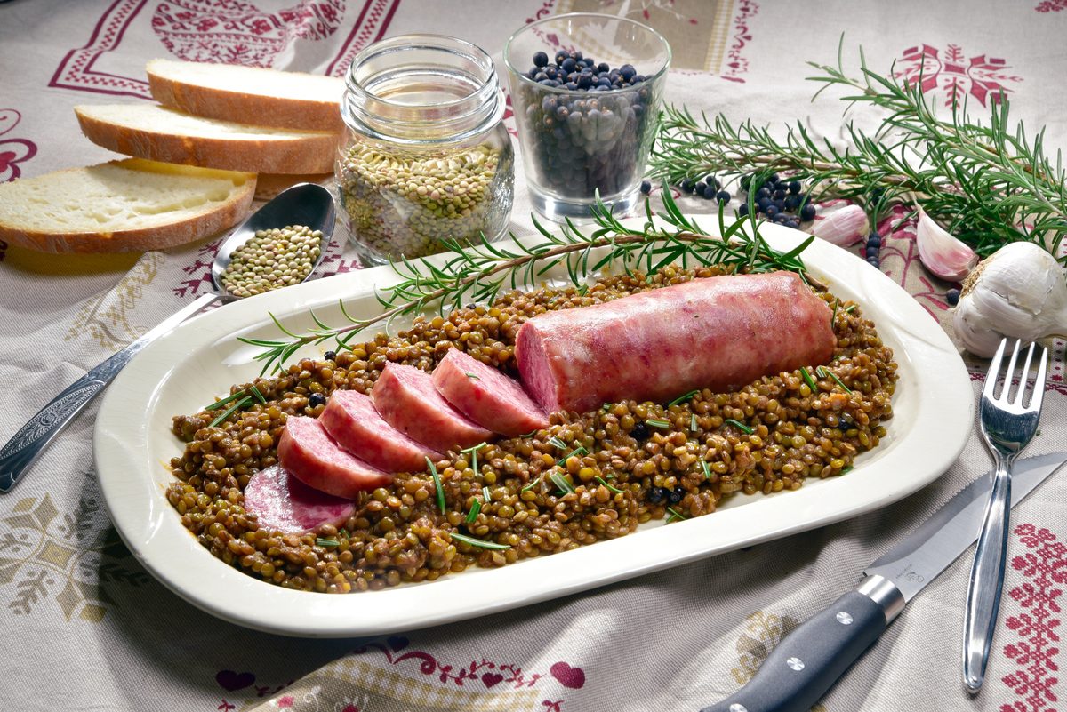 Sliced cotechino sausage on a bed of lentils with rosemary