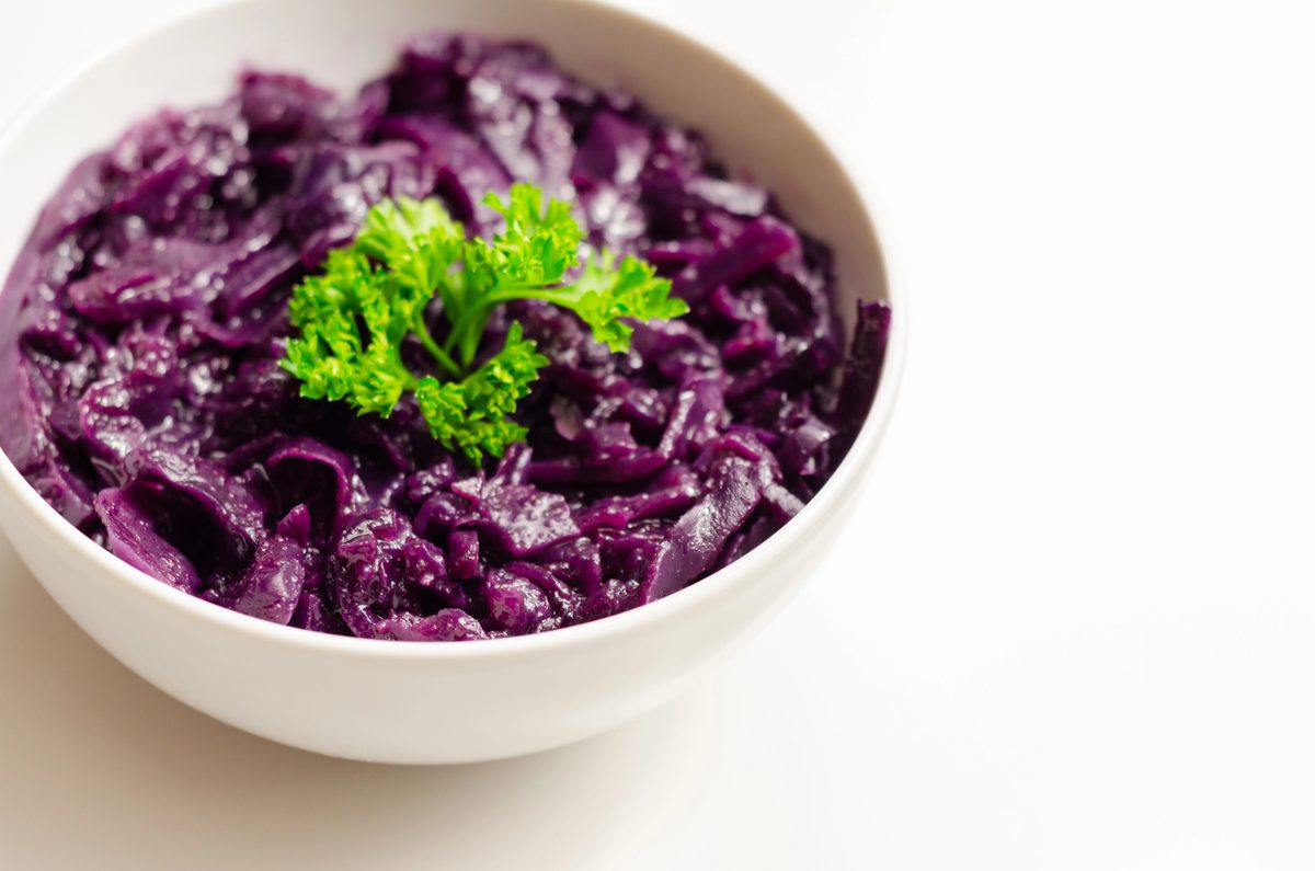 Braised red cabbage in a white bowl, garnished with parsley