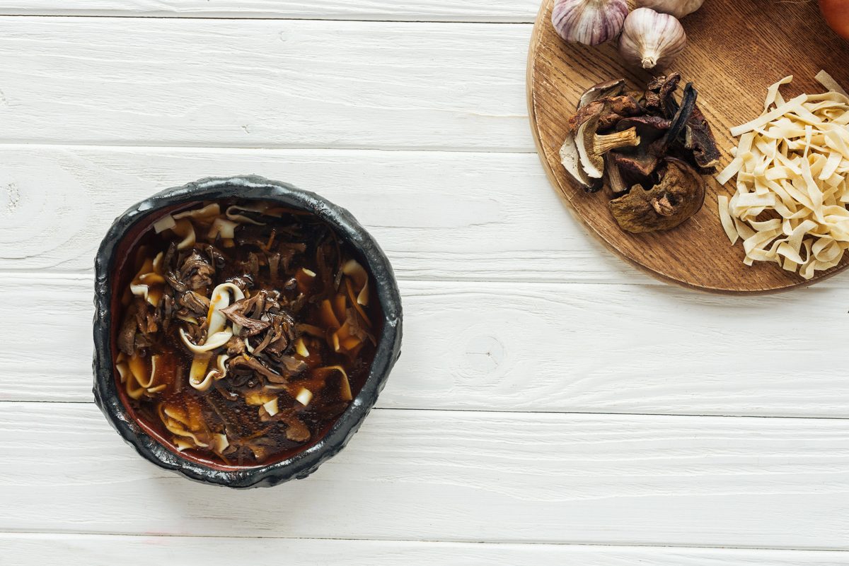 Dark wild mushroom soup in a bowl with dried mushrooms