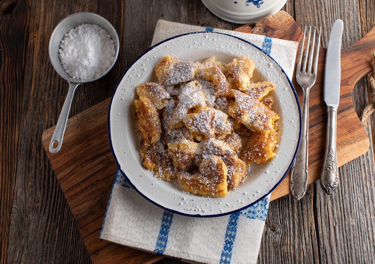 Torn pancake dusted with powdered sugar on a white plate