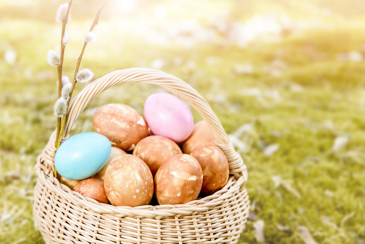 Easter eggs dyed brown with onion skins in a wicker basket on grass