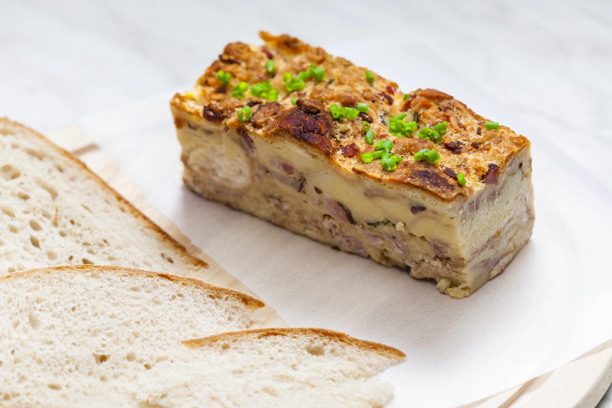 Slice of baked Easter bread roll with ham and herbs