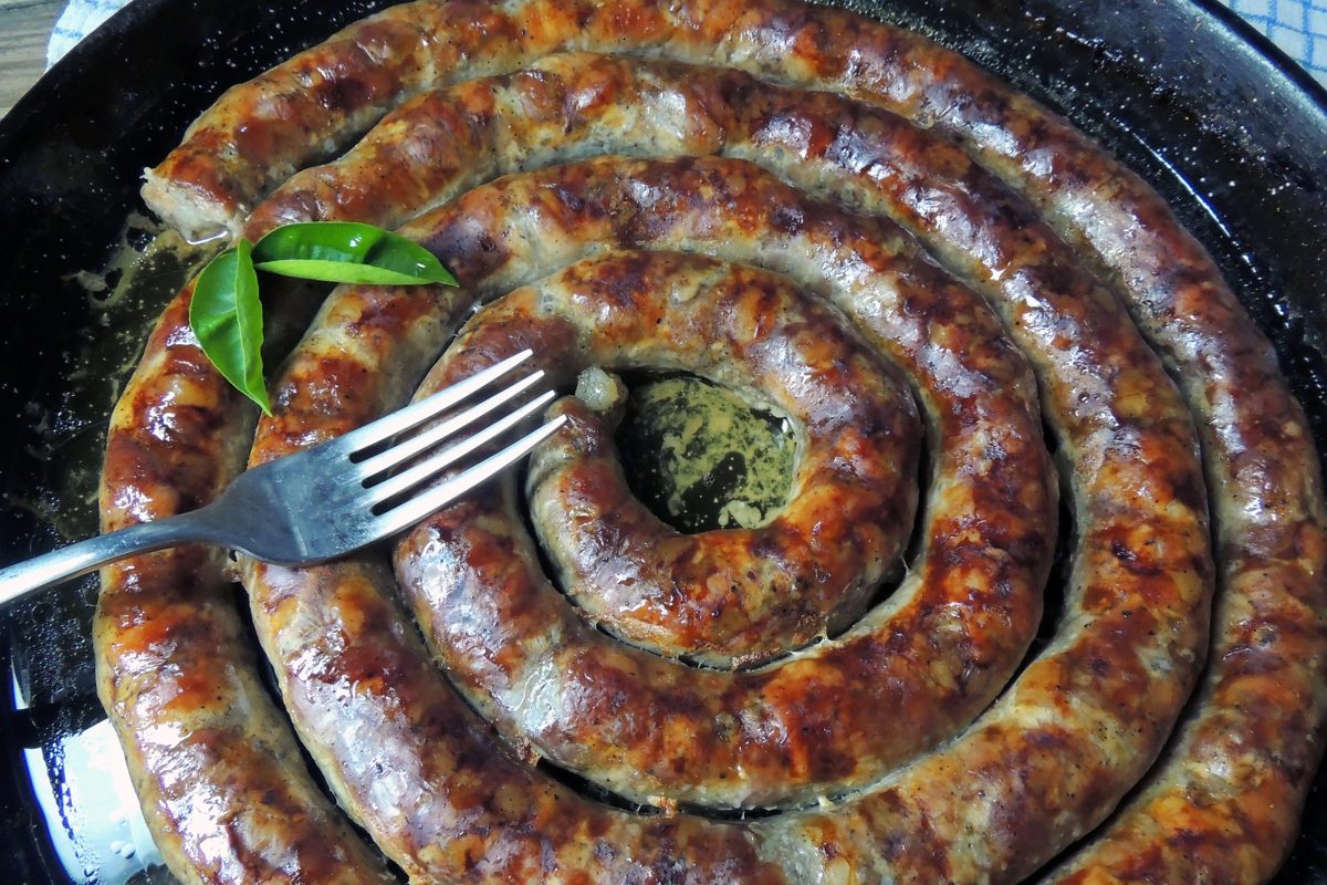Coil of roasted white sausage in a pan