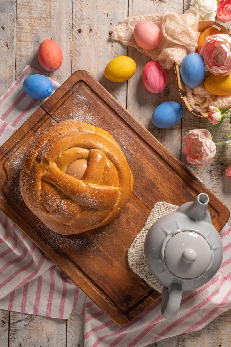 Round folar Easter bread on a wooden board with Easter eggs