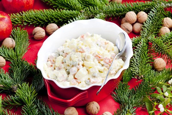 Czech potato salad in a red bowl among fir branches and walnuts