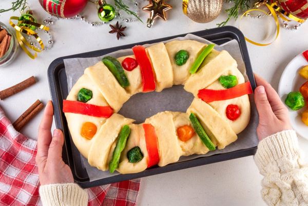 Roscón de Reyes ring cake with candied fruit, sliced on a festive table