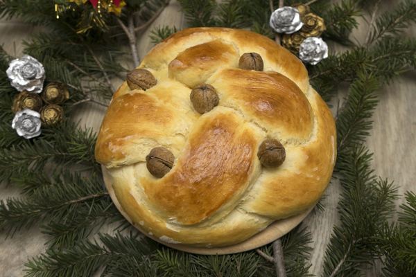 Round Christopsomo bread decorated with a dough cross and walnuts