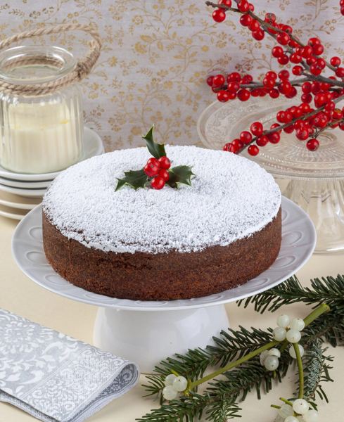Vasilopita New Year's cake dusted with powdered sugar beside Christmas decorations