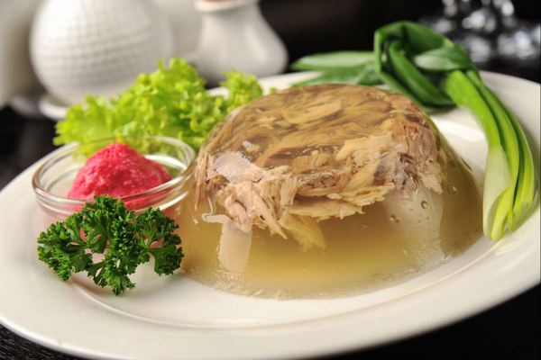 Kocsonya meat aspic on a plate with herbs and vegetables