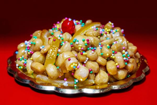 Struffoli, small fried dough balls glazed with honey and colored sprinkles, on a platter