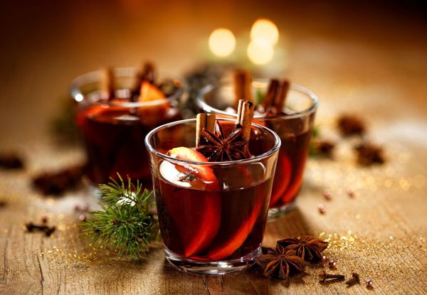 Glasses of vin brulé mulled wine with orange and spices by candlelight