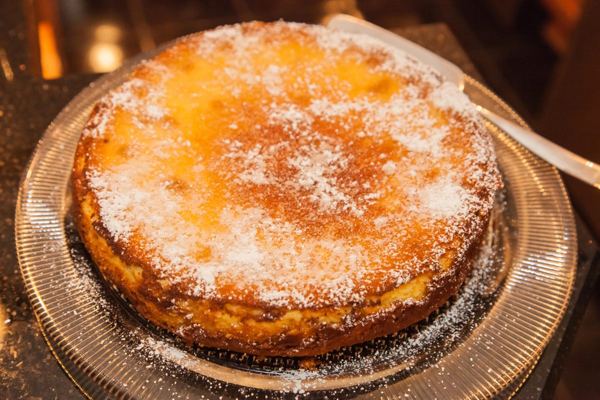 Whole Polish cheesecake with a golden top on a festive table
