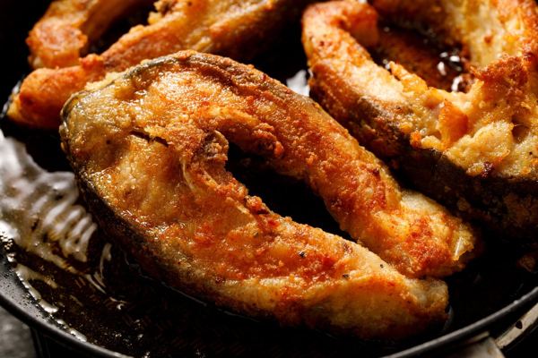 Fried carp steaks on a dark plate