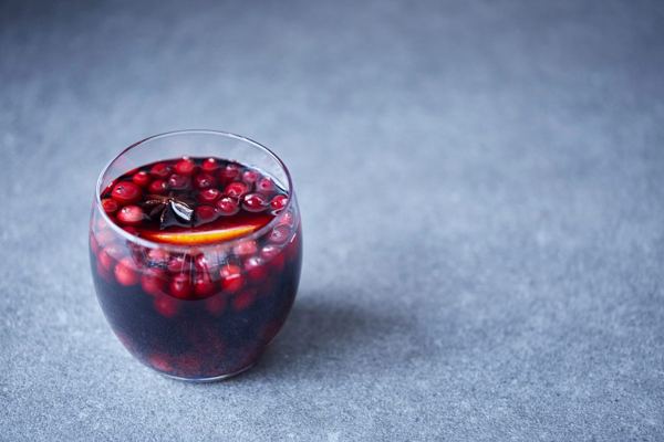 Glass of hot mulled wine with cranberries and orange