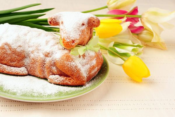 Lamb-shaped Easter cake dusted with powdered sugar, with spring tulips