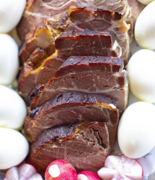 Sliced Easter ham with boiled eggs and radishes